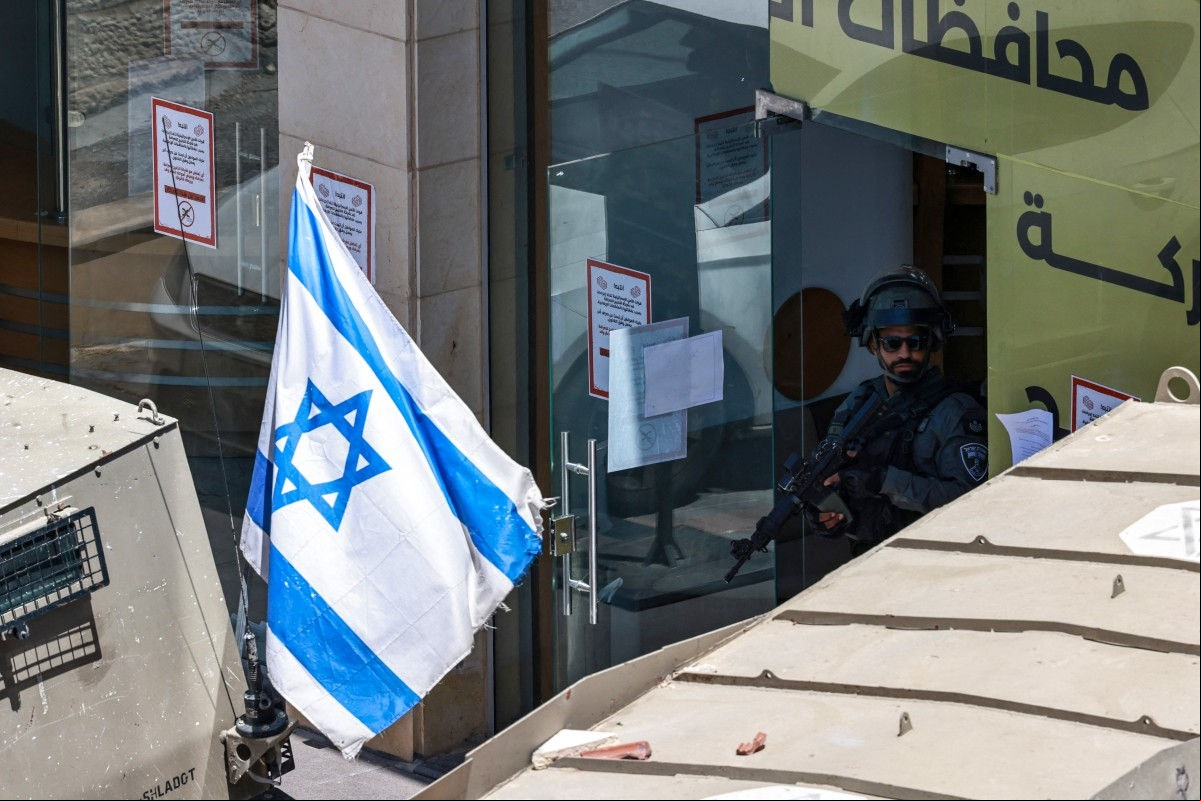 Soldado israelense em um banco na Cisjordânia ocupada | Foto: Zain Jaafar/AFP